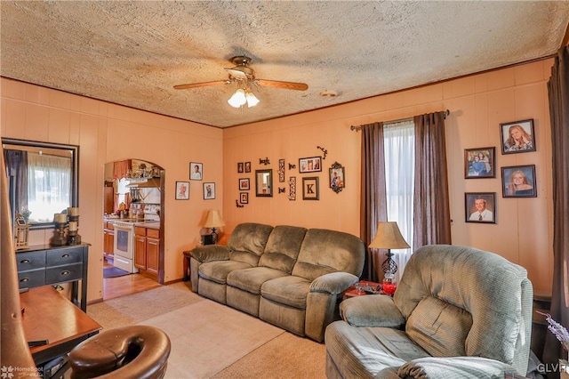 living room featuring light carpet, ceiling fan, and a textured ceiling