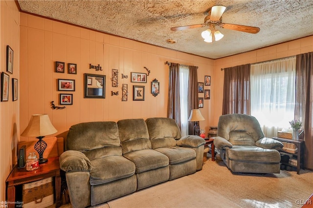 carpeted living room with ceiling fan, wood walls, and a textured ceiling