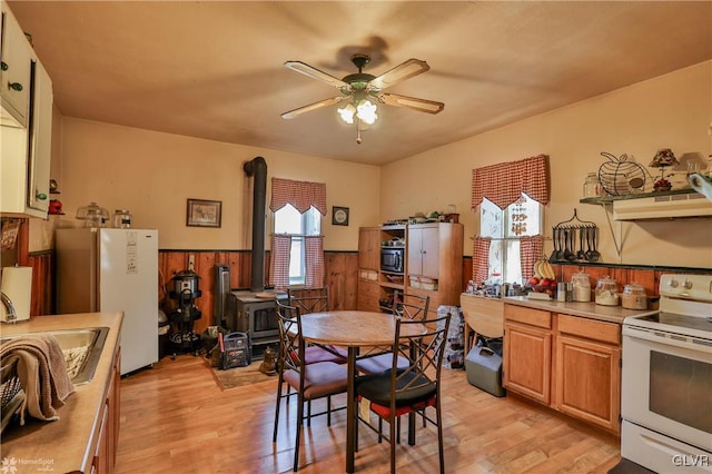 dining room with sink, light wood-type flooring, ceiling fan, and wood walls