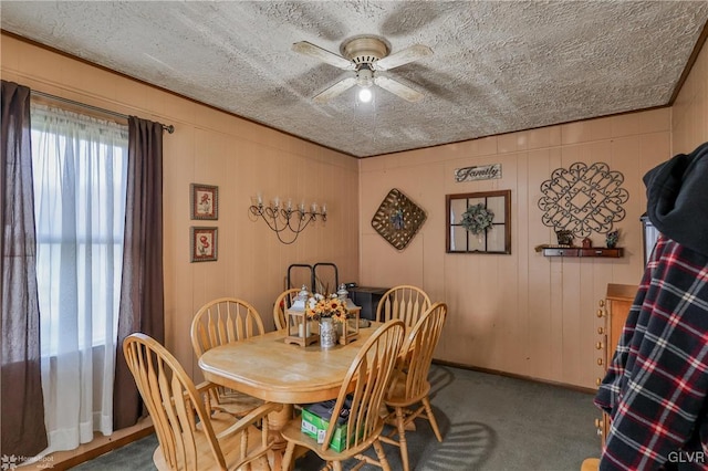 dining space featuring ceiling fan, wood walls, carpet floors, and a textured ceiling