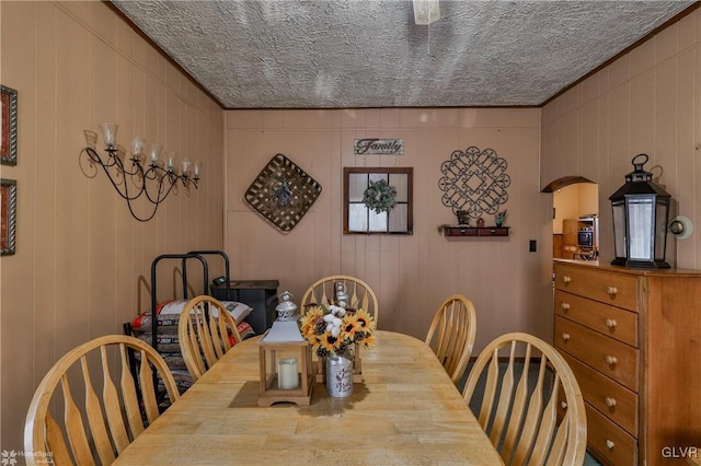 dining area with wooden walls and a textured ceiling