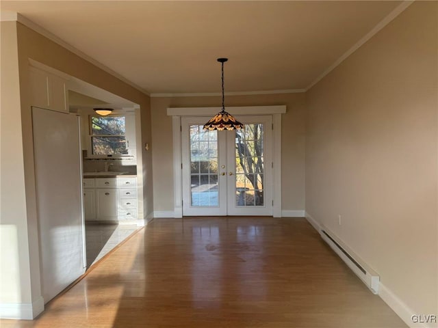 unfurnished dining area featuring crown molding, french doors, light hardwood / wood-style floors, and a baseboard heating unit