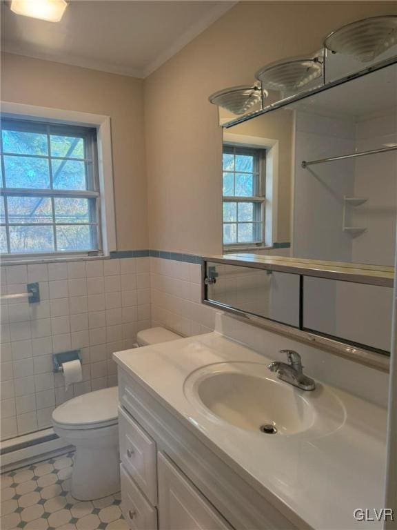 bathroom featuring toilet, vanity, baseboard heating, and tile walls