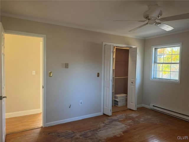 unfurnished bedroom featuring hardwood / wood-style floors, a walk in closet, crown molding, ceiling fan, and a closet