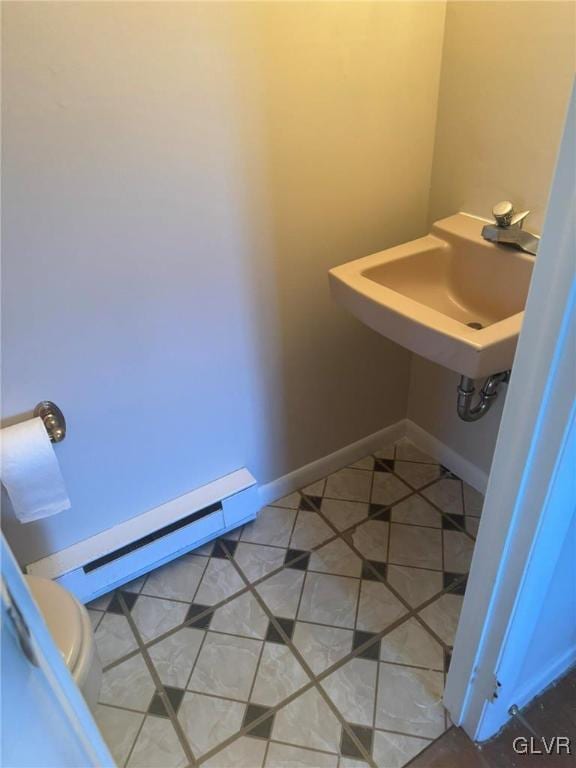 bathroom featuring tile patterned flooring, toilet, baseboard heating, and sink