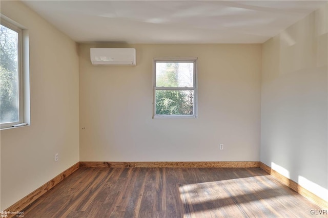 unfurnished room with a wall mounted AC, a healthy amount of sunlight, and dark hardwood / wood-style floors