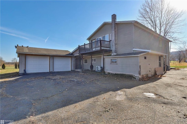 back of house with central AC unit, a garage, and a balcony