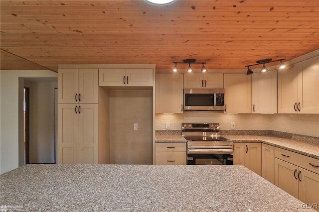 kitchen featuring rail lighting, wooden ceiling, light stone counters, decorative backsplash, and appliances with stainless steel finishes