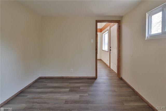 empty room with plenty of natural light and dark hardwood / wood-style flooring