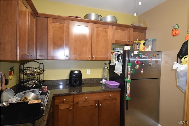 kitchen with stainless steel refrigerator and dark stone counters