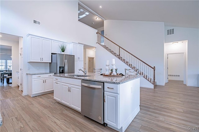 kitchen with a center island with sink, white cabinets, stainless steel appliances, and sink