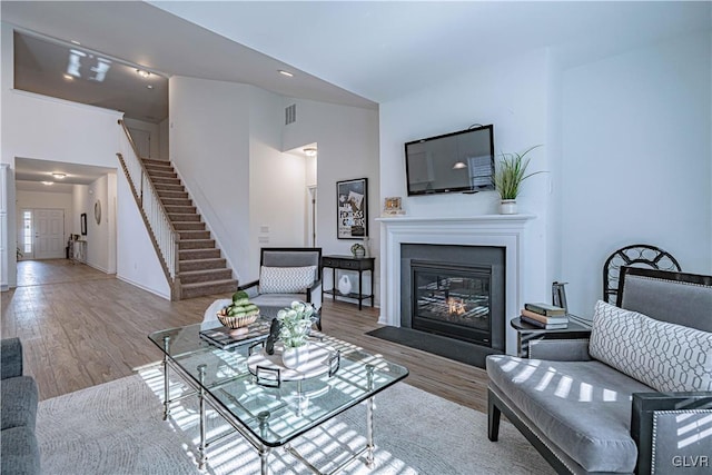 living room with high vaulted ceiling and light wood-type flooring