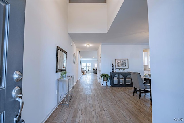 entrance foyer with a high ceiling, light wood-type flooring, and crown molding