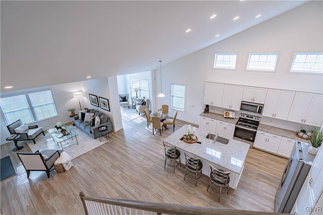 kitchen with plenty of natural light, light hardwood / wood-style floors, white cabinetry, and appliances with stainless steel finishes