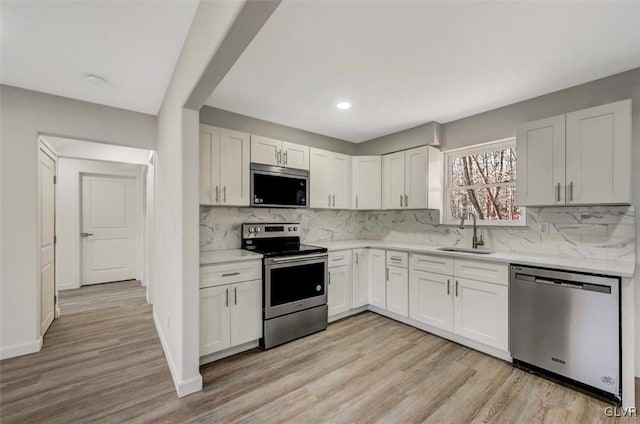 kitchen with sink, white cabinets, stainless steel appliances, and light hardwood / wood-style floors