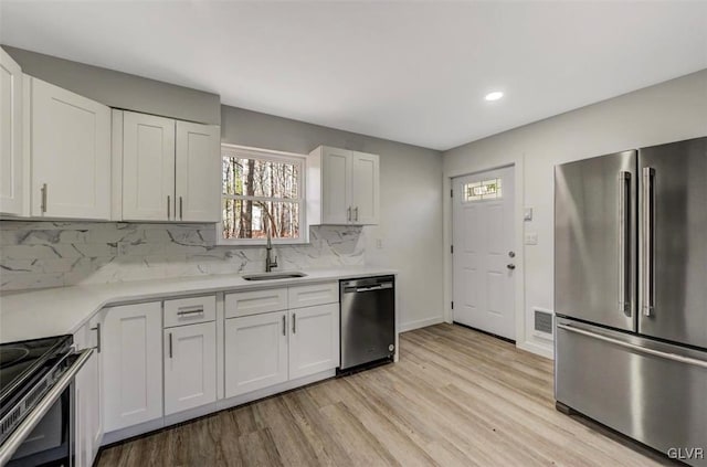 kitchen featuring sink, white cabinetry, stainless steel appliances, and light hardwood / wood-style flooring