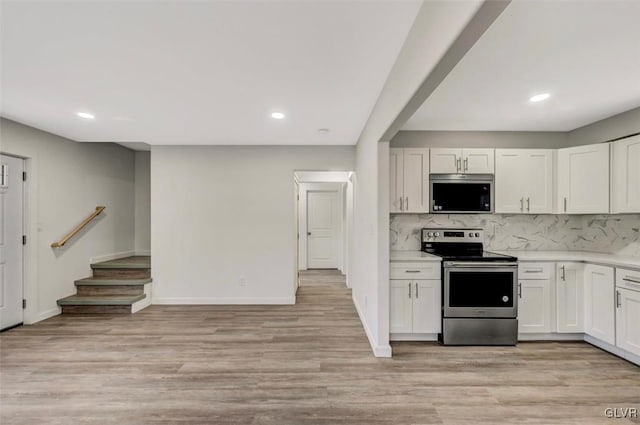 kitchen with decorative backsplash, white cabinets, light hardwood / wood-style floors, and appliances with stainless steel finishes