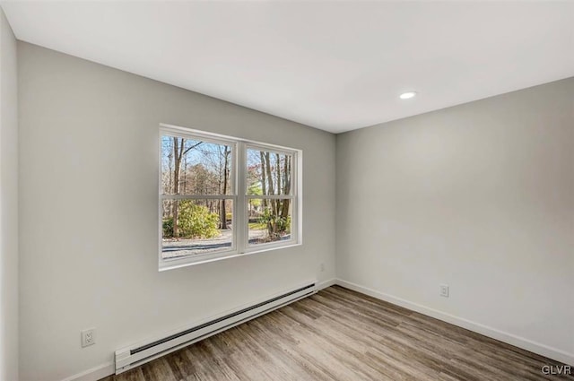 spare room featuring wood-type flooring and baseboard heating