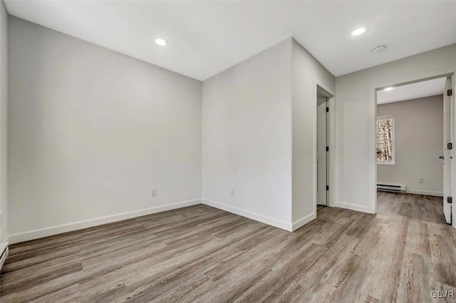 unfurnished room featuring a baseboard radiator and light hardwood / wood-style flooring