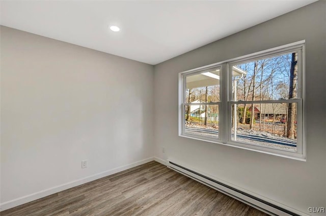 unfurnished room with wood-type flooring and baseboard heating