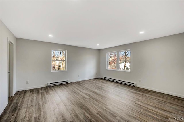 spare room with a wealth of natural light, wood-type flooring, and a baseboard heating unit