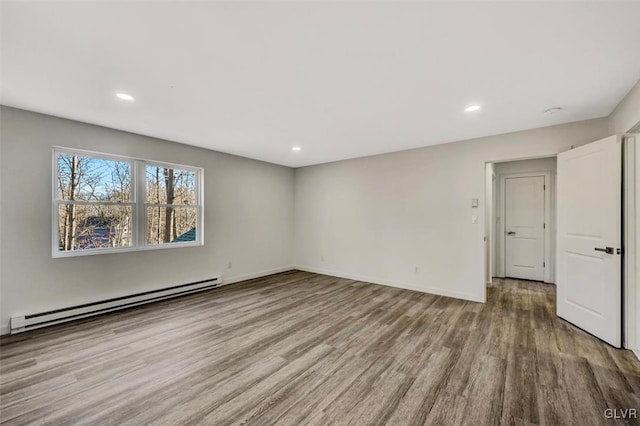 empty room with hardwood / wood-style flooring and a baseboard heating unit