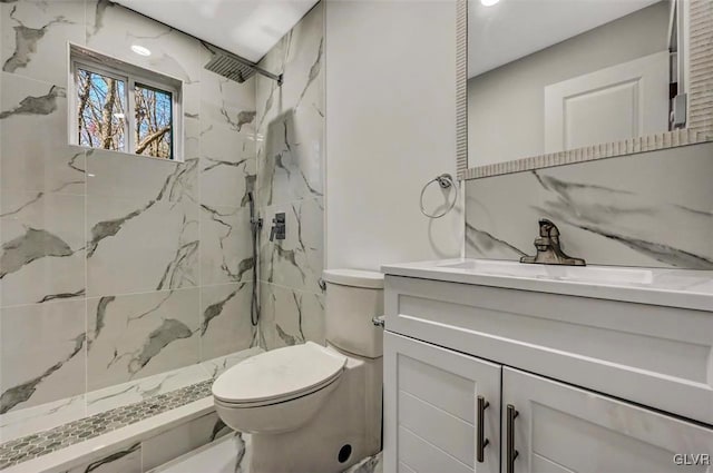 bathroom with tiled shower, vanity, and toilet