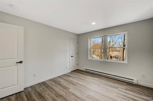 empty room with a baseboard radiator and light hardwood / wood-style floors