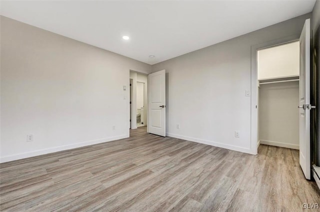 unfurnished bedroom with light hardwood / wood-style floors, a spacious closet, and a closet