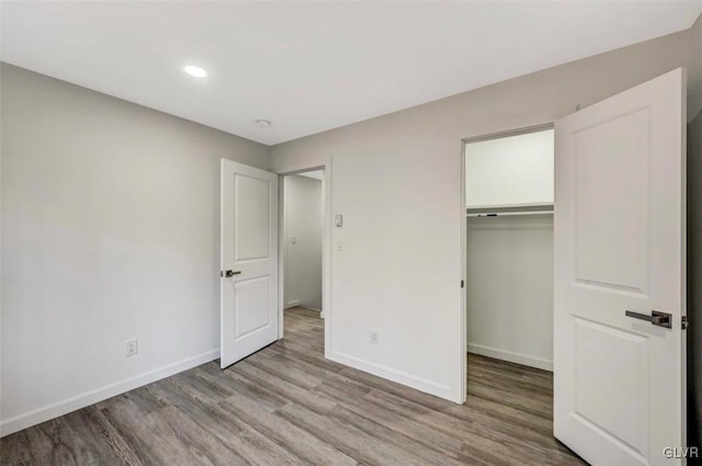 unfurnished bedroom with a walk in closet, a closet, and light hardwood / wood-style floors