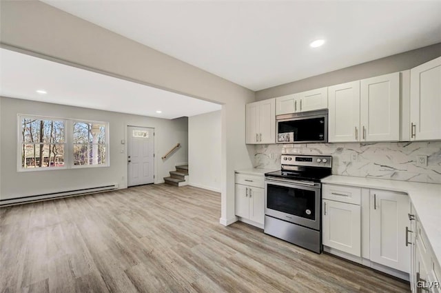 kitchen with white cabinets, light hardwood / wood-style floors, stainless steel appliances, and a baseboard radiator