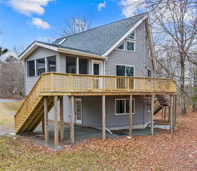 rear view of property featuring a sunroom and a wooden deck