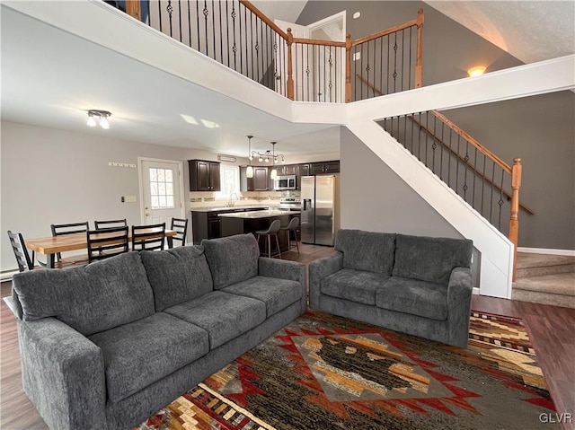 living room with sink, light hardwood / wood-style flooring, and high vaulted ceiling