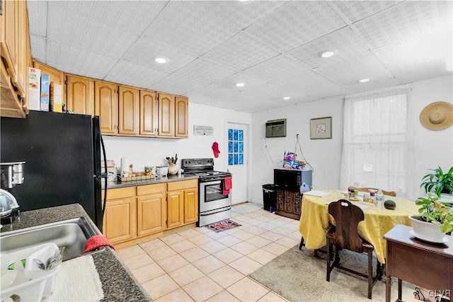 kitchen with sink, light tile patterned floors, black fridge, a wall mounted AC, and stainless steel range with electric cooktop