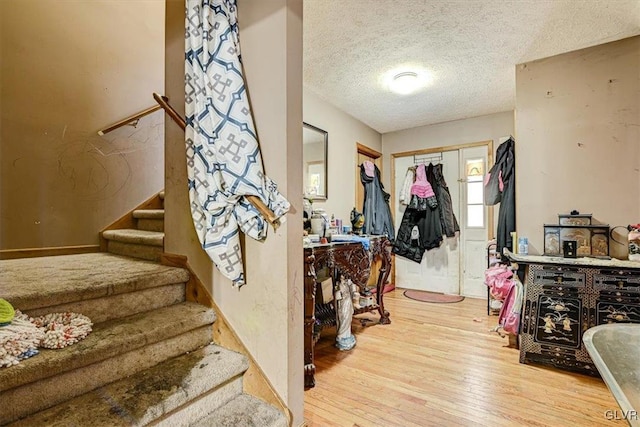 foyer entrance with a textured ceiling and light hardwood / wood-style flooring