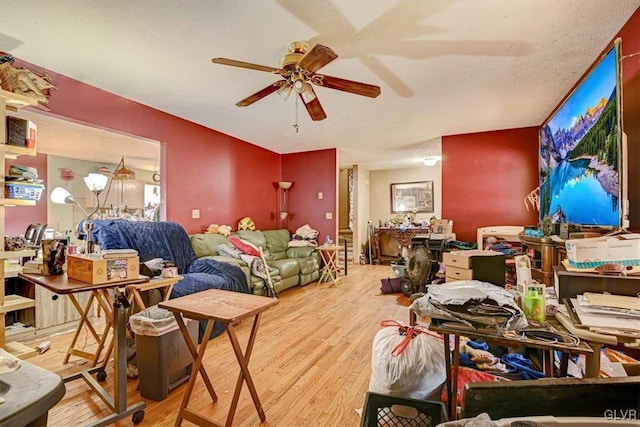 living room with a textured ceiling, hardwood / wood-style flooring, and ceiling fan