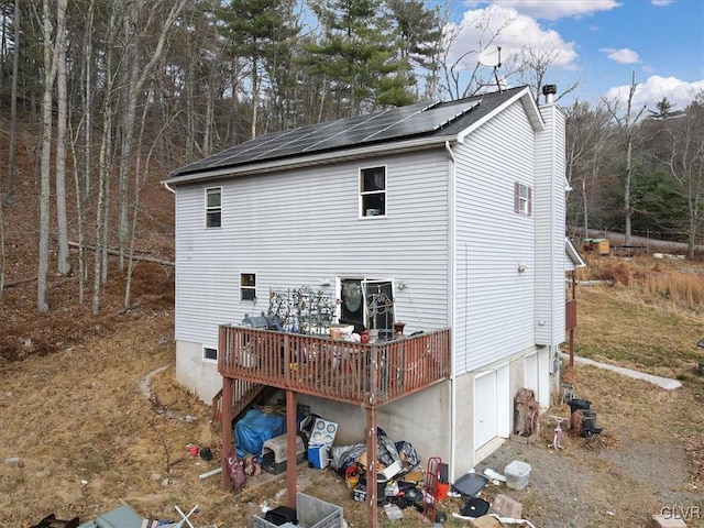 view of property exterior featuring solar panels, a wooden deck, and a garage