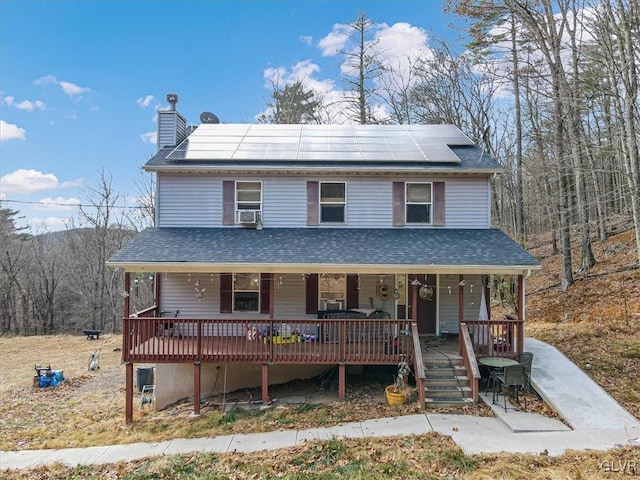 view of front of property with cooling unit, a porch, and solar panels