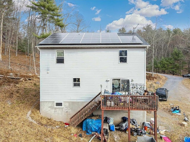 back of house featuring solar panels and a wooden deck