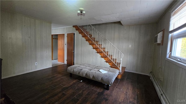 staircase featuring baseboard heating, wooden walls, wood-type flooring, and a wall mounted air conditioner