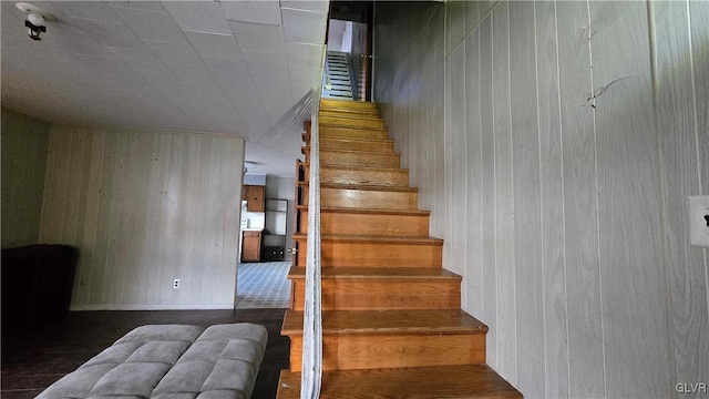 staircase featuring wooden walls and wood-type flooring