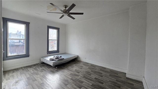 spare room with plenty of natural light, ceiling fan, and dark hardwood / wood-style flooring