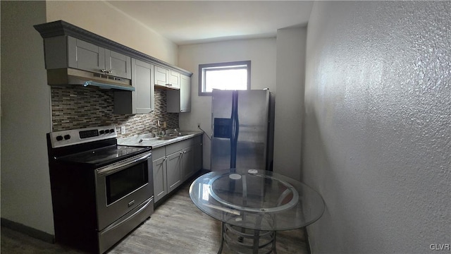 kitchen with decorative backsplash, appliances with stainless steel finishes, light hardwood / wood-style floors, sink, and gray cabinets