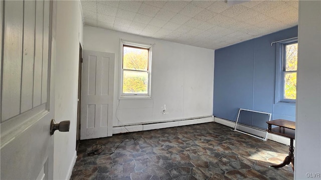 unfurnished room with plenty of natural light and a baseboard heating unit