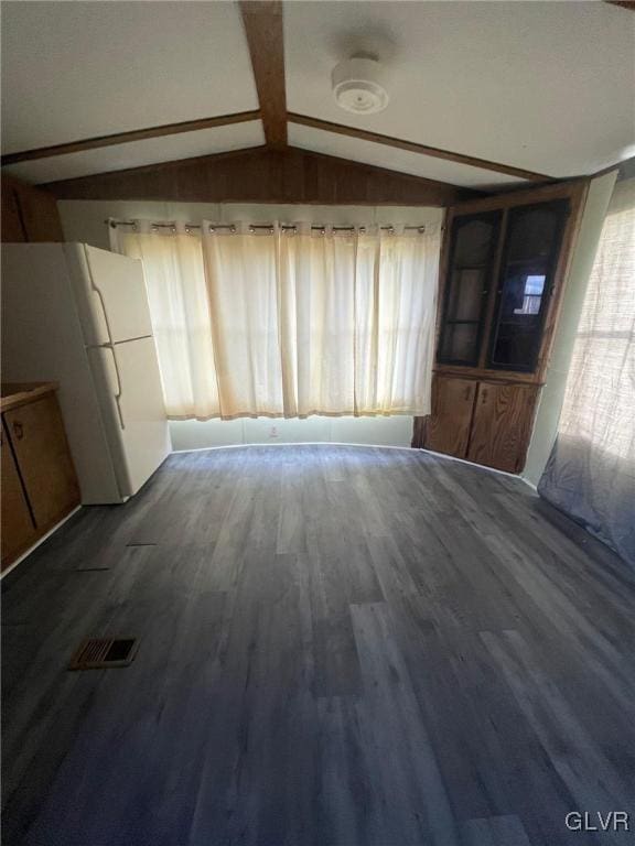 unfurnished living room featuring vaulted ceiling with beams and dark hardwood / wood-style floors