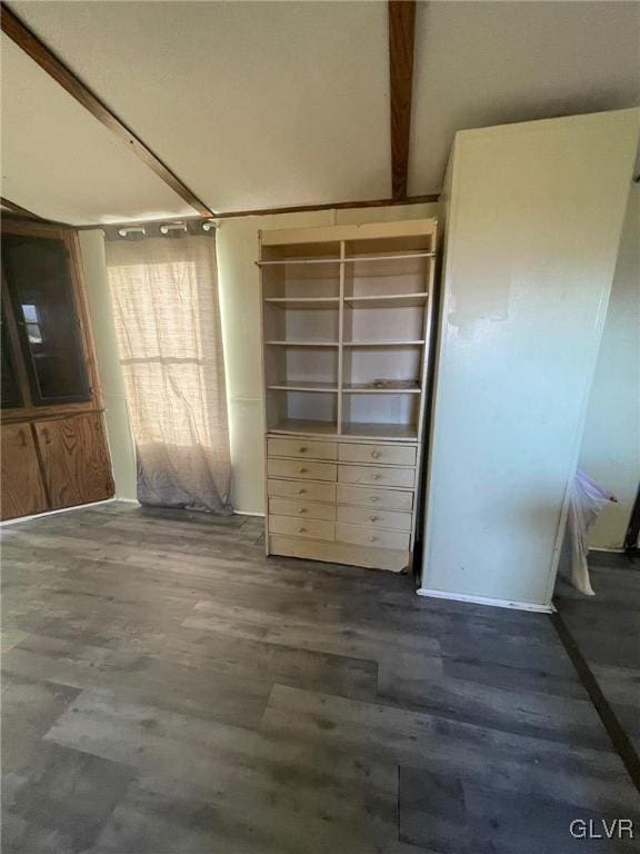 unfurnished bedroom featuring beamed ceiling and dark hardwood / wood-style floors