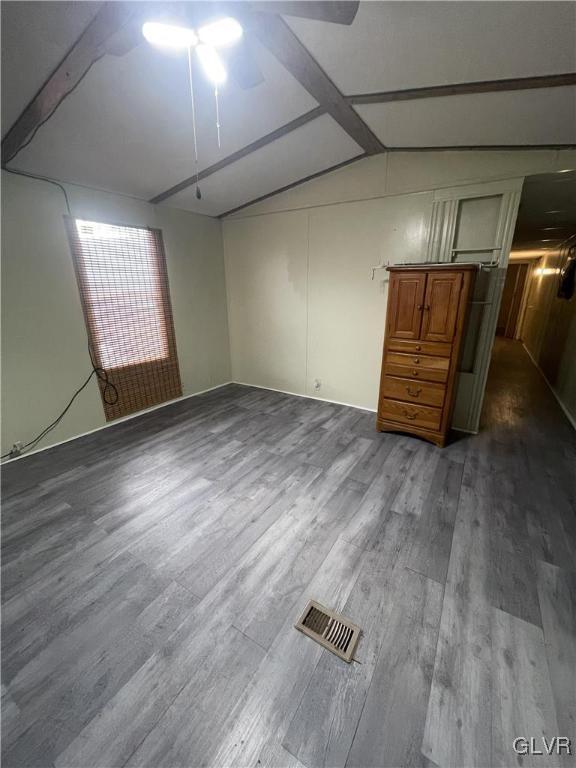 empty room with dark hardwood / wood-style flooring and lofted ceiling with beams