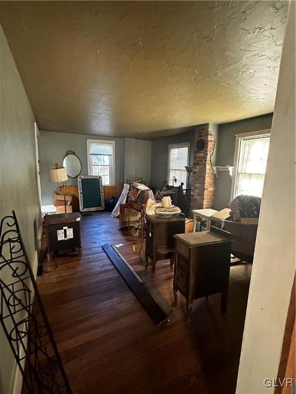 interior space with a textured ceiling, dark hardwood / wood-style floors, and a healthy amount of sunlight