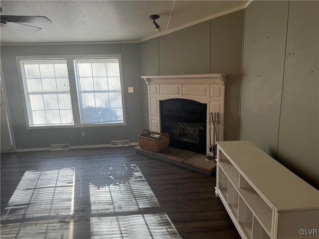 unfurnished living room with ceiling fan, dark hardwood / wood-style flooring, and a textured ceiling