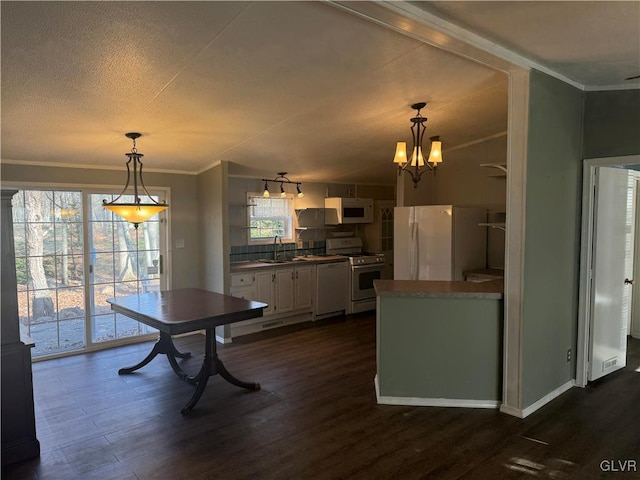 dining space with ornamental molding, a textured ceiling, dark wood-type flooring, sink, and a chandelier